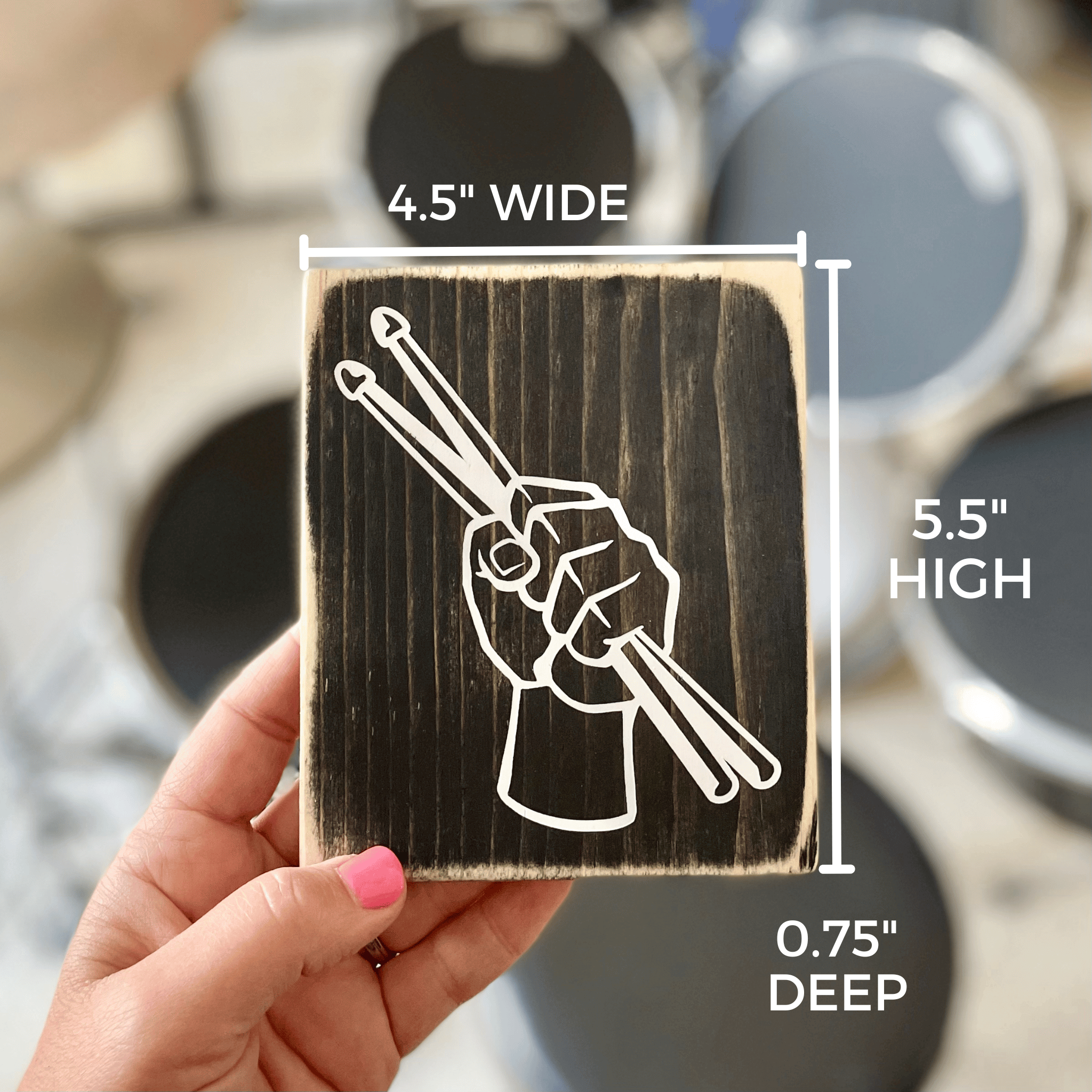 Shows dimensions of the drumsticks in a fist sign which are 4.5" wide, 5.5" high and 0.5" deep