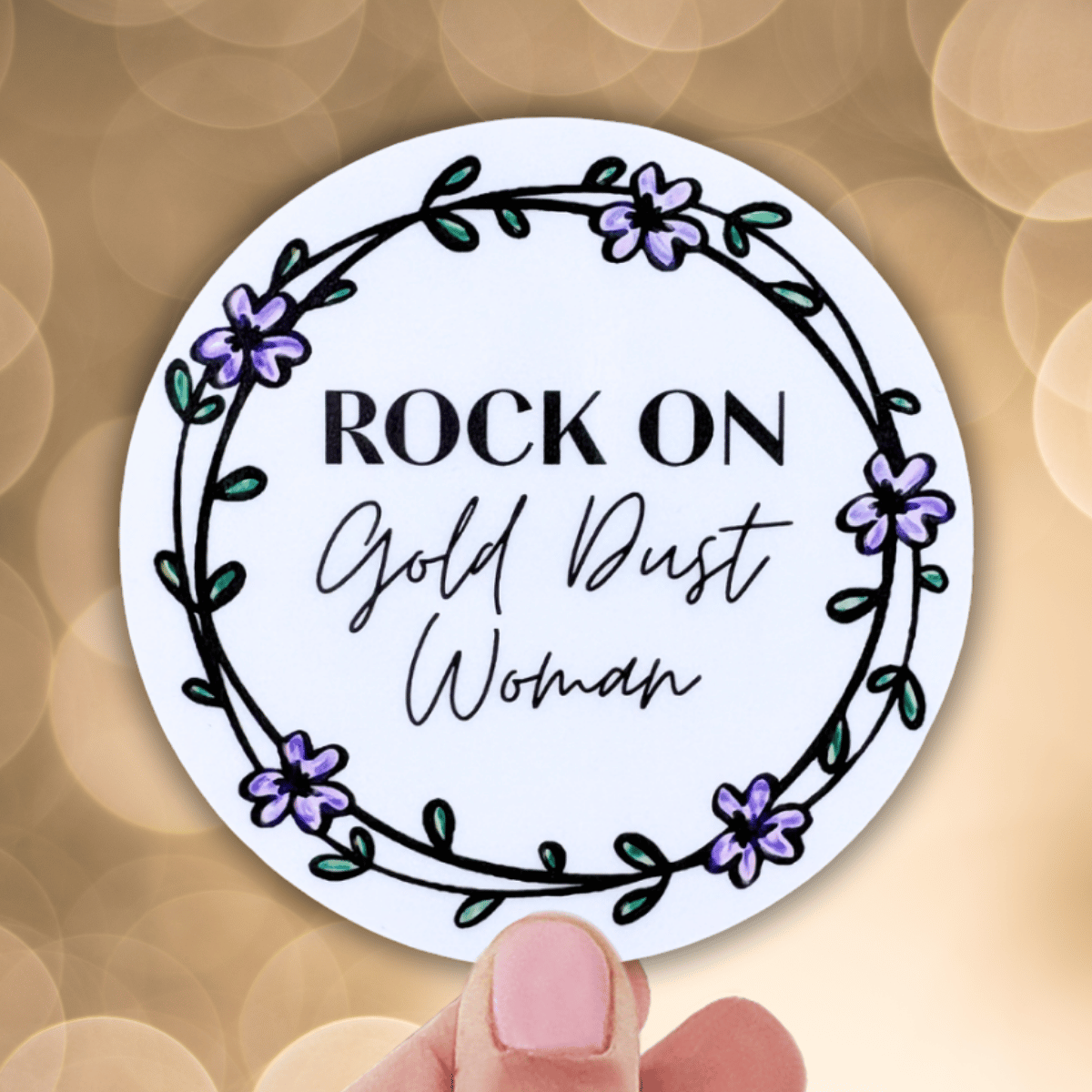 Circular sticker with floral design and text held against a blurred background