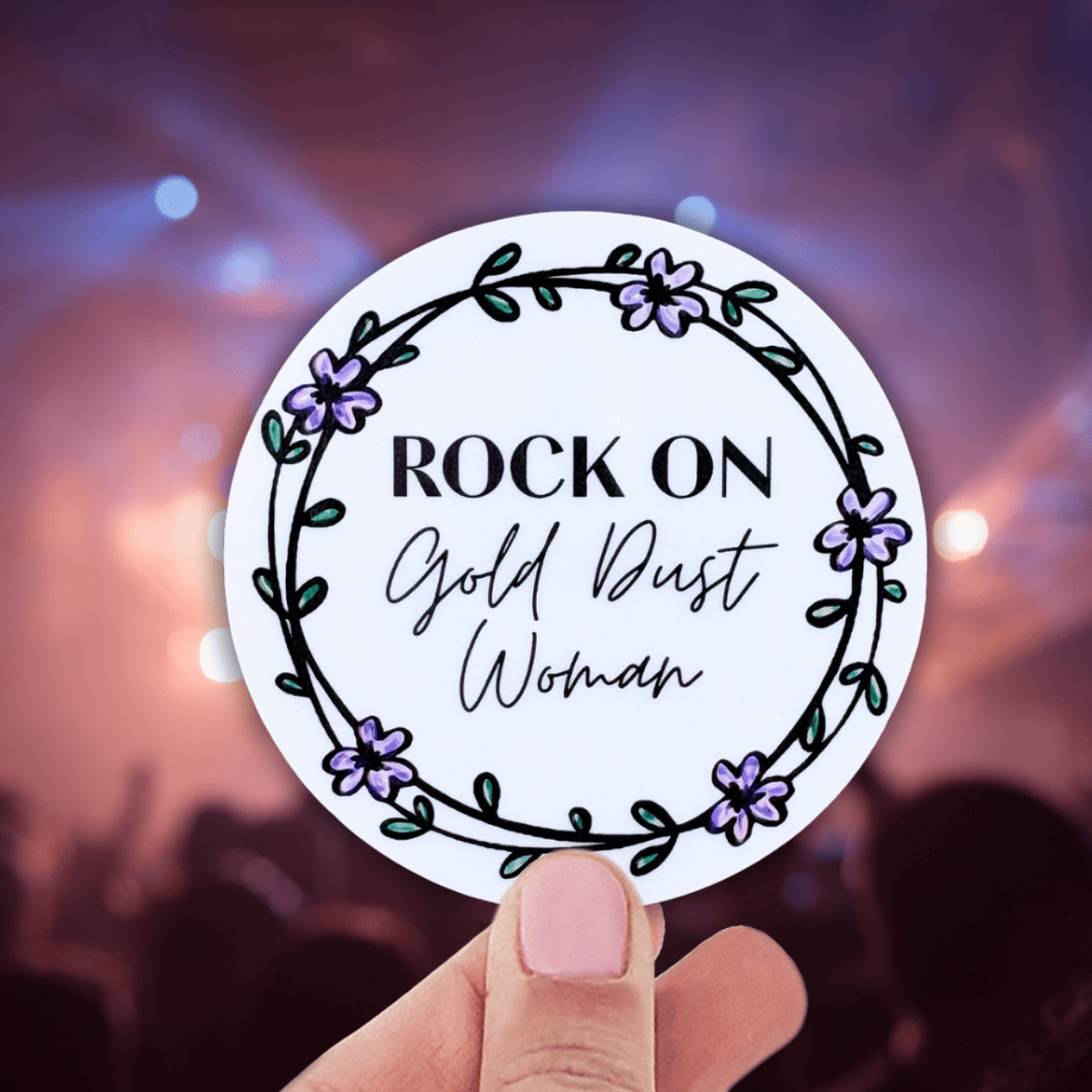 Circular sticker with 'Rock On Gold Dust Woman' text held against a concert background