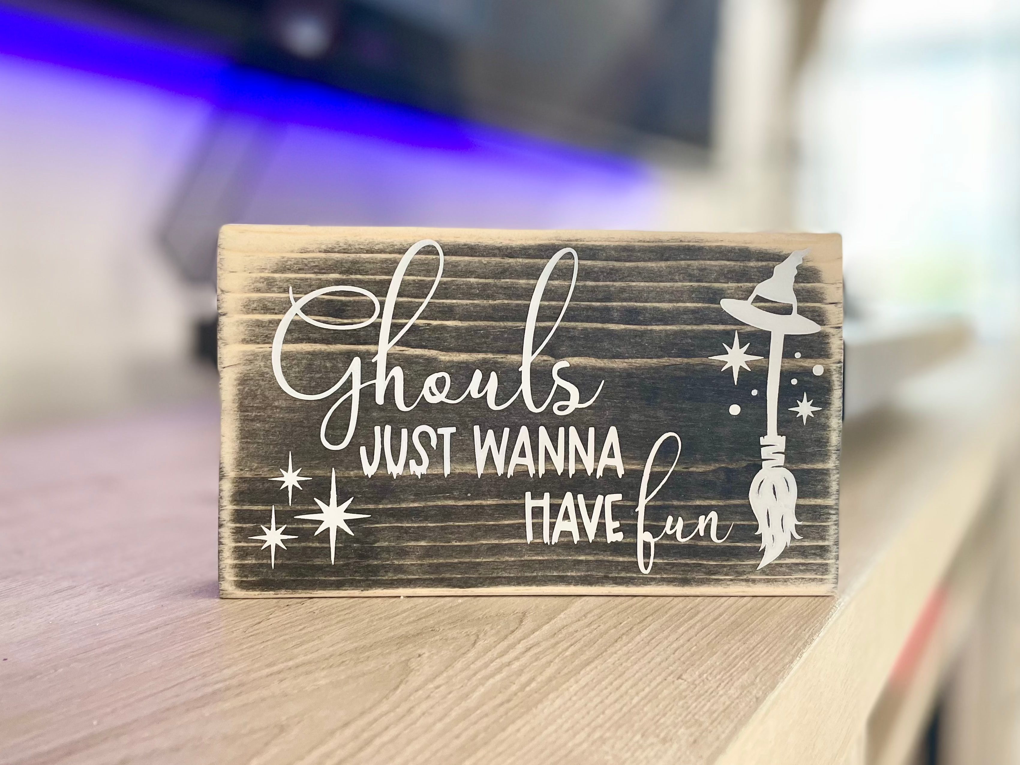 A small, black, wood sign sits on a table in front of a record player.