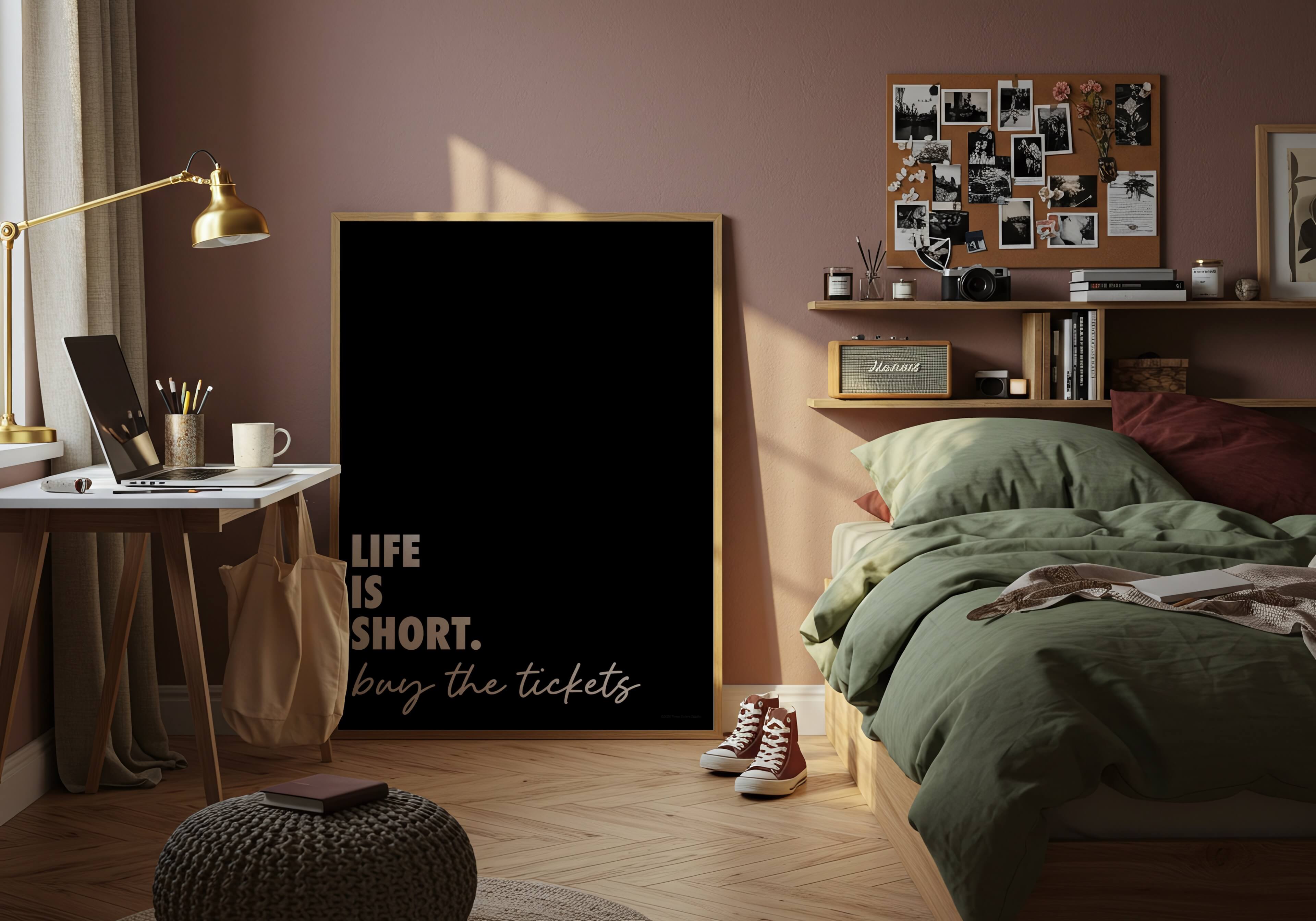 A large vertical black poster with a gold frame stands in a styled dorm room. The poster features the quote 'LIFE IS SHORT.