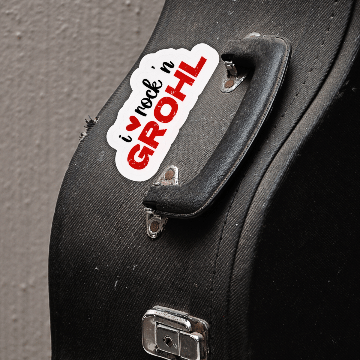 The "I love Rock n Grohl" sticker is on the side of a black guitar case