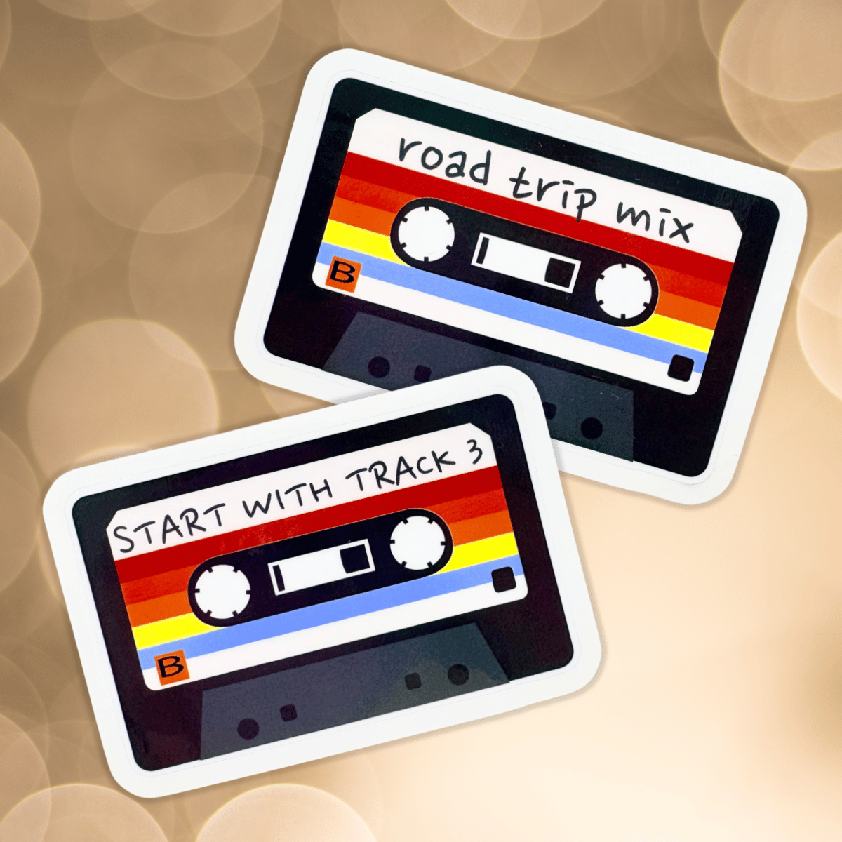 Two retro-style cassette tape stickers with text on a blurred, gold background