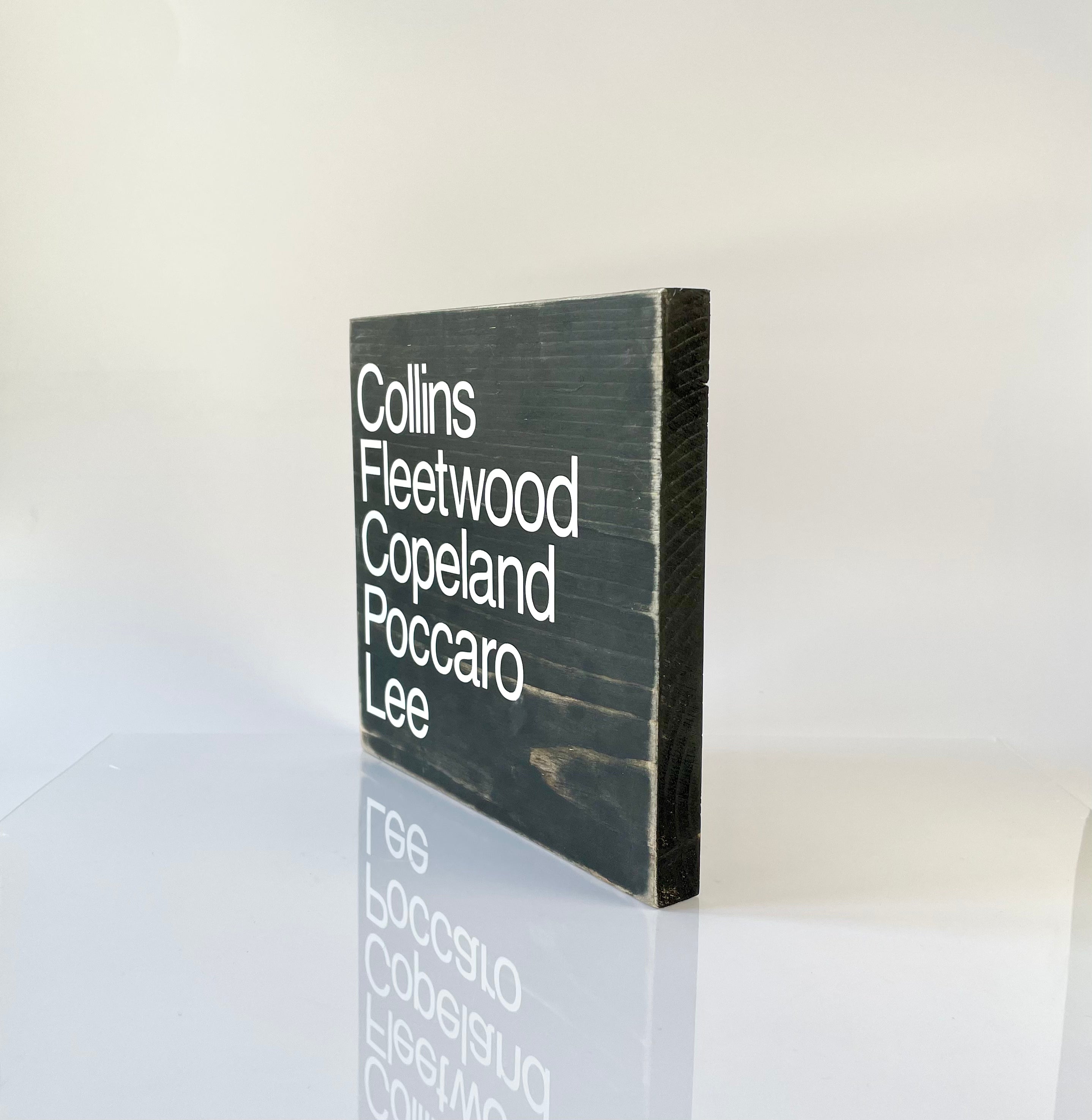 A side view of a black, wood sign sitting on a white surface.