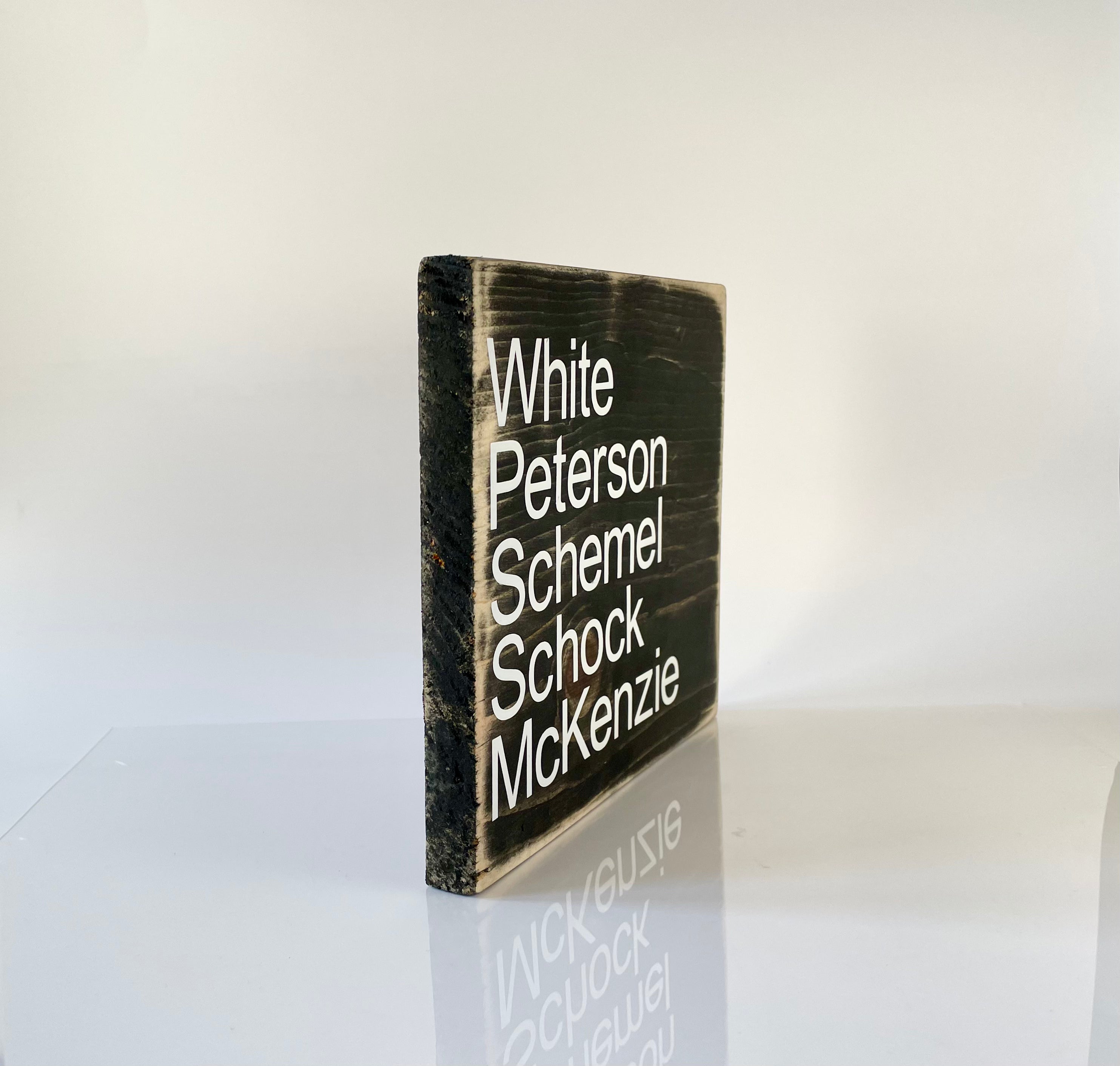 A side view of a black, wood sign sitting on a white table