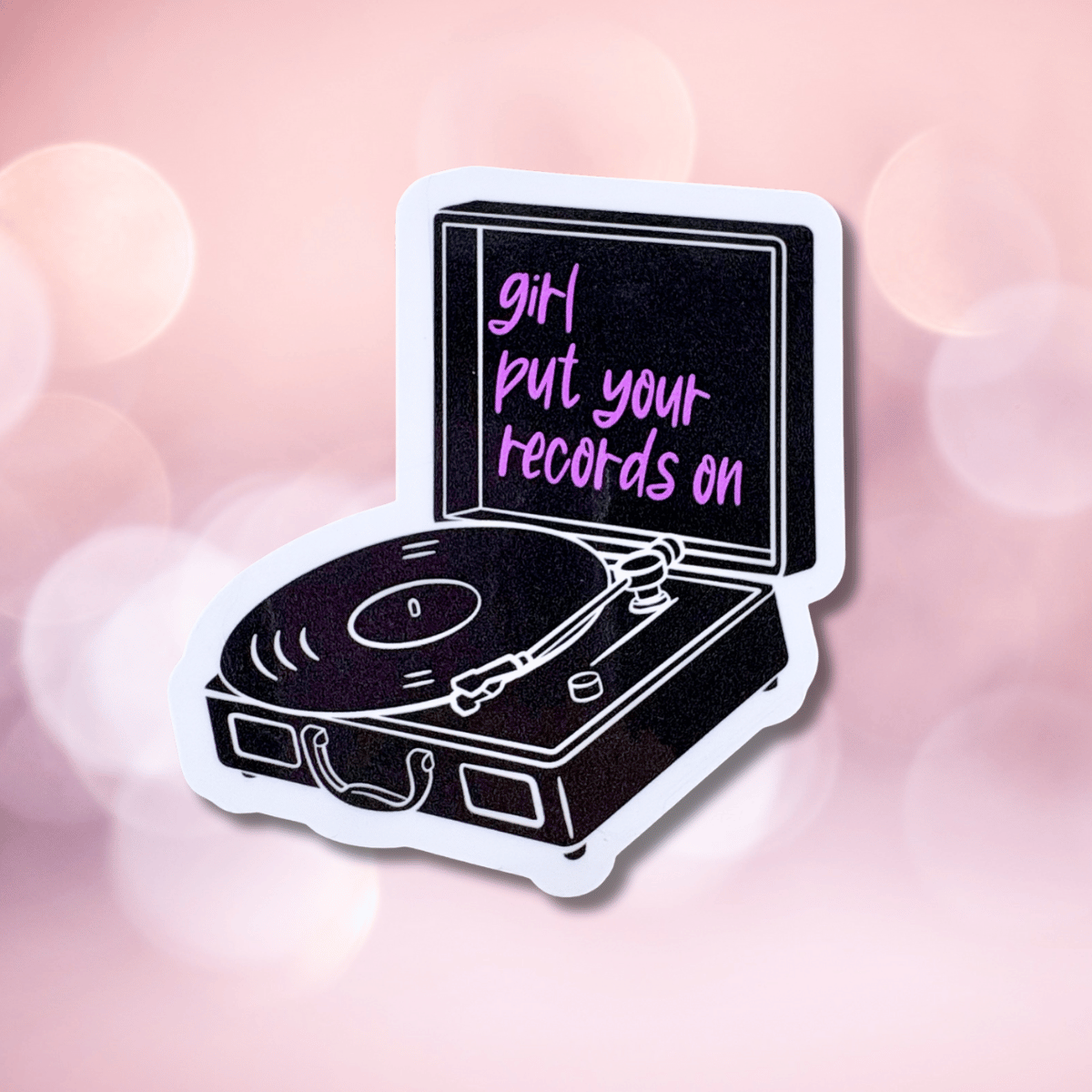 Vinyl record player sticker with 'girl put your records on' text on a pink blurred background