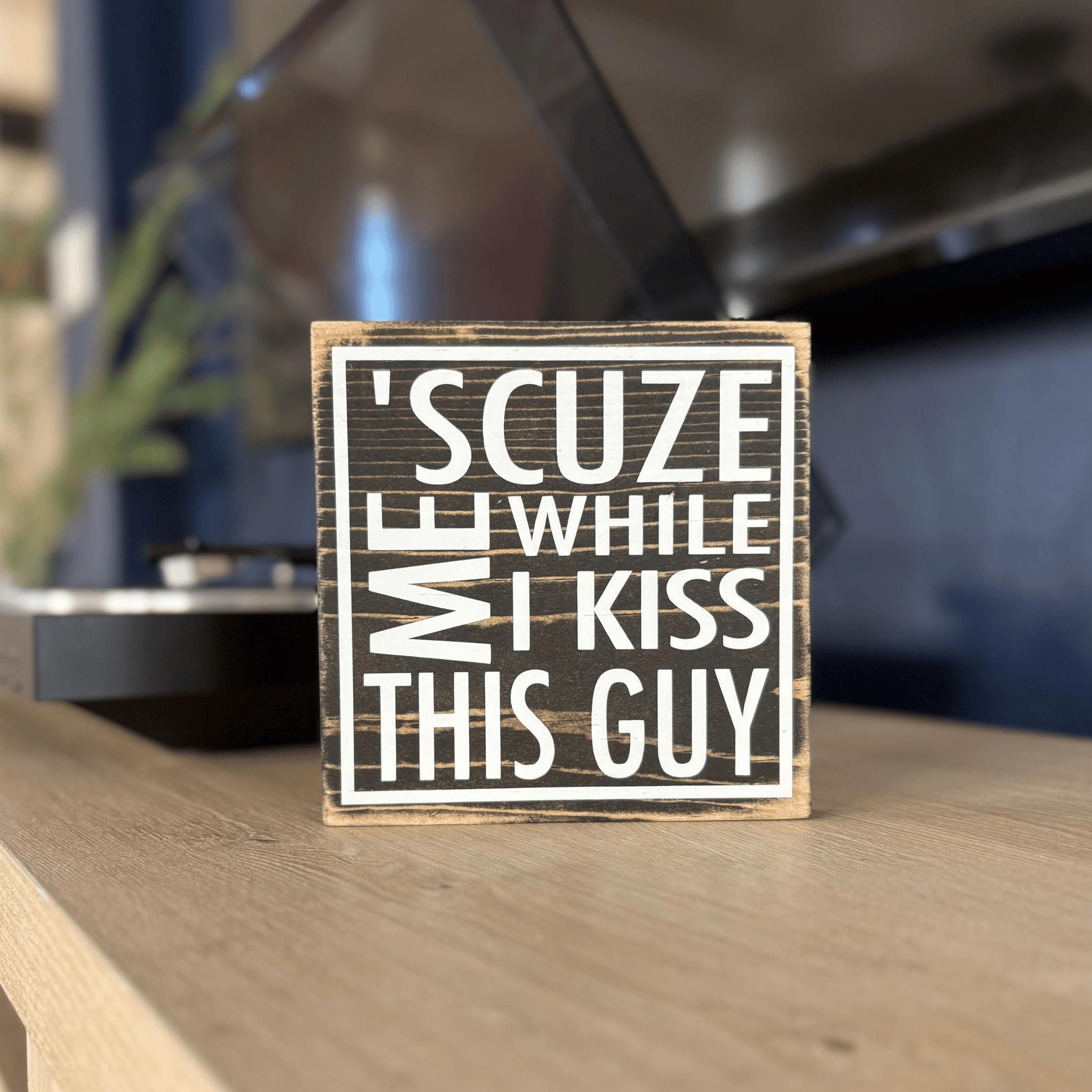 Wooden sign with humorous text on a wooden surface