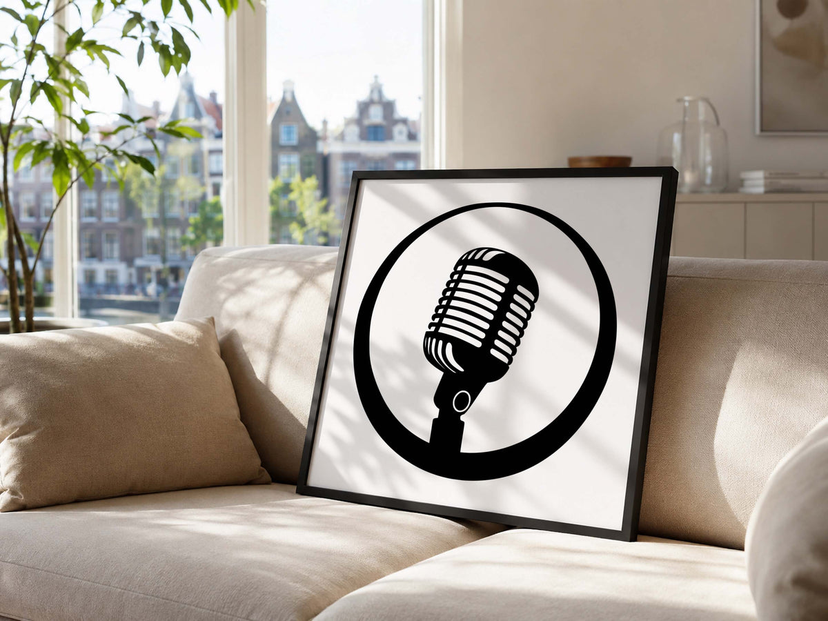 A framed black and white graphic print featuring a retro microphone inside a circle, leaning against a beige sofa in a bright living room with a window and city view.