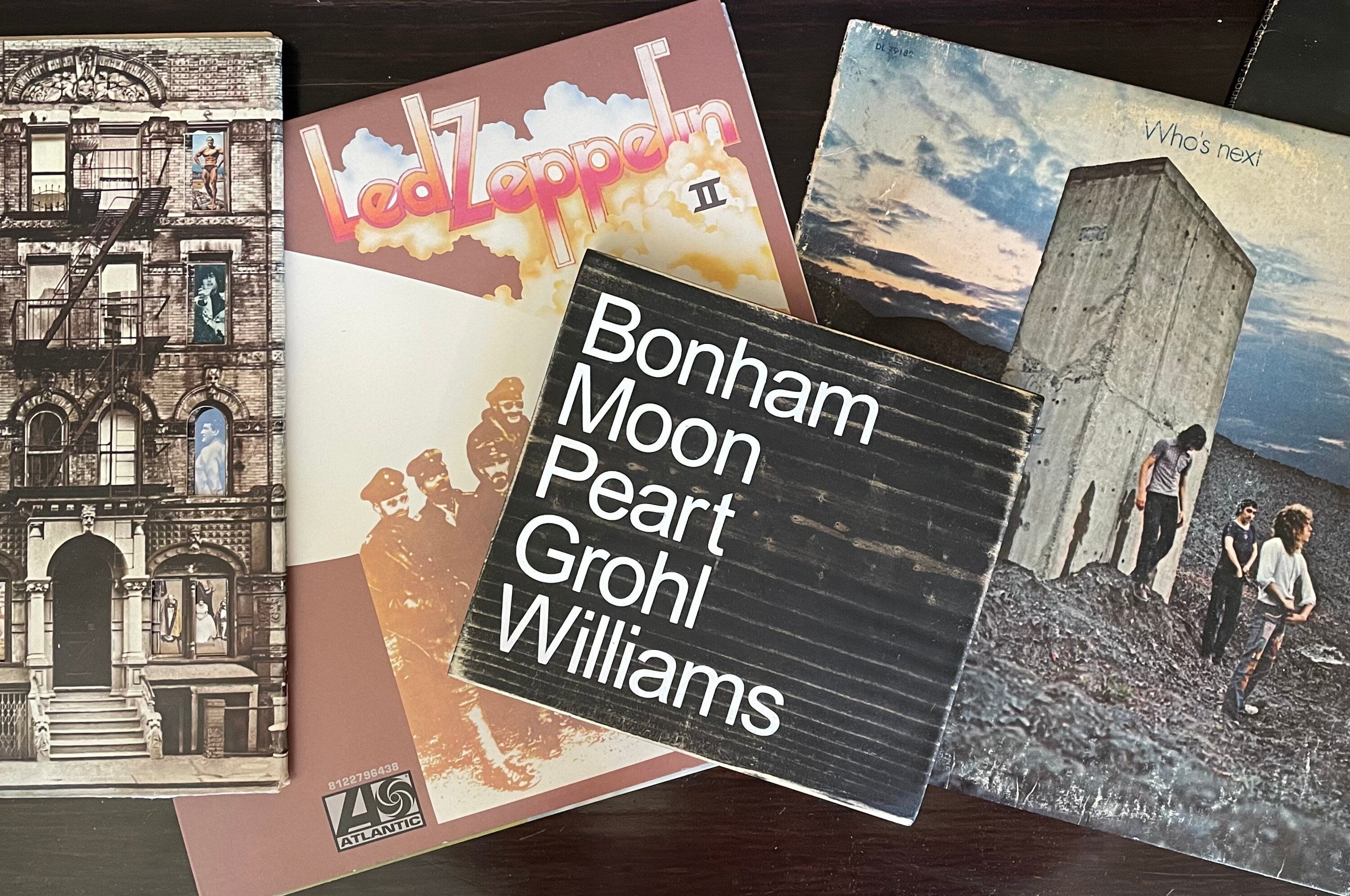A black, wood sign sits on top of Led Zeppelin and the Doors album covers.