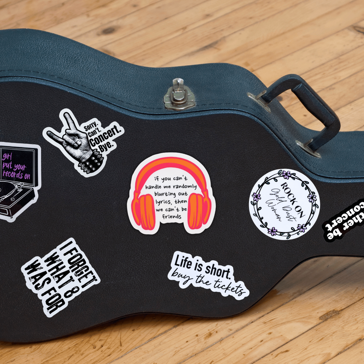 Black guitar case with various stickers on a wooden floor