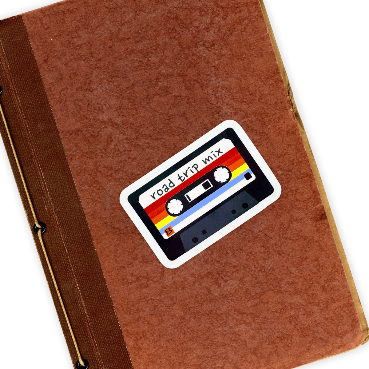 Brown notebook with a 'road trip mix' cassette tape sticker on a white background