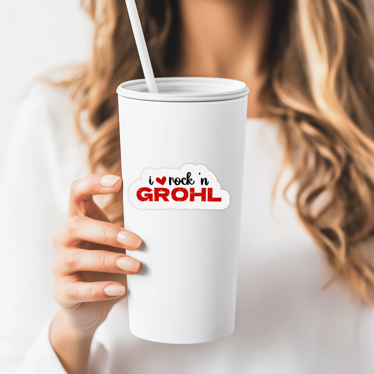 A woman is holding a white tumbler that has the "I love Rock n Grohl" sticker on it. 