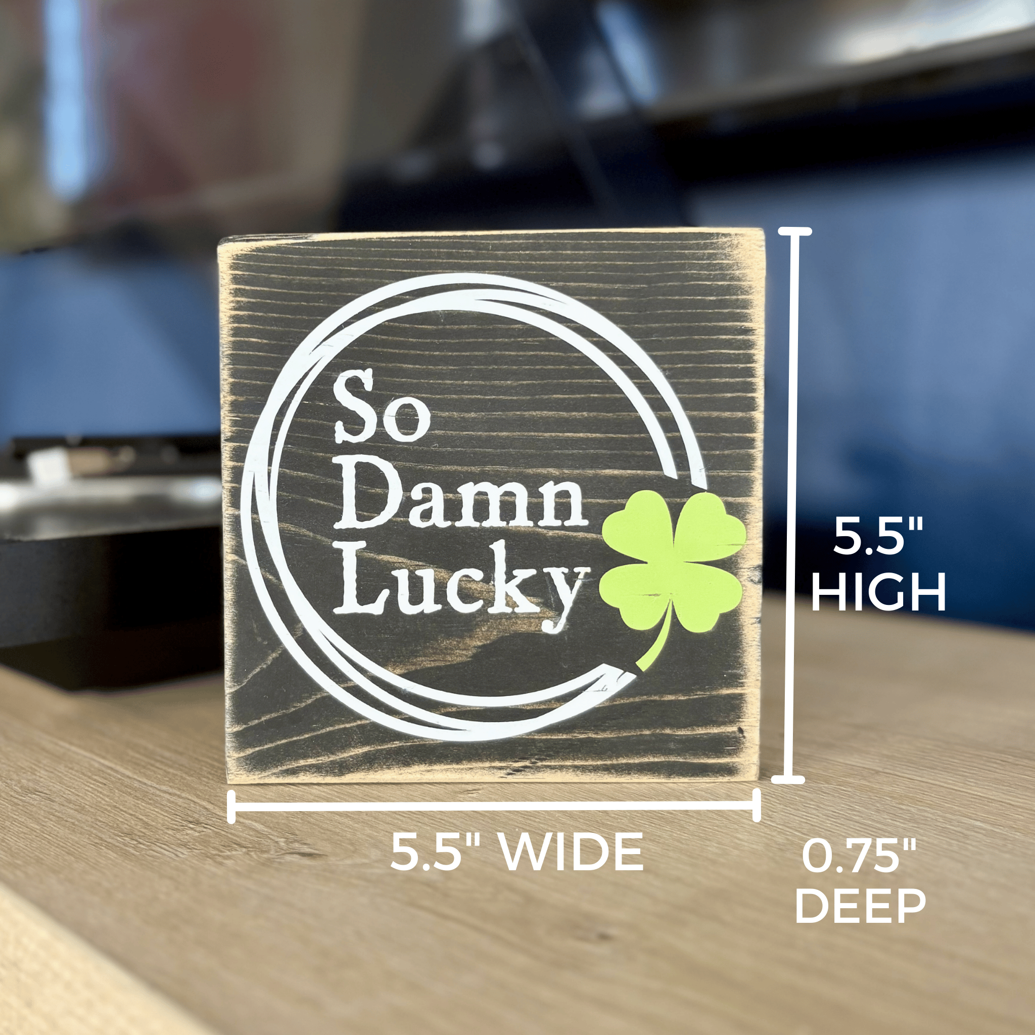 Wooden block with 'So Damn Lucky' text and a four-leaf clover, showing dimensions on a wooden surface.