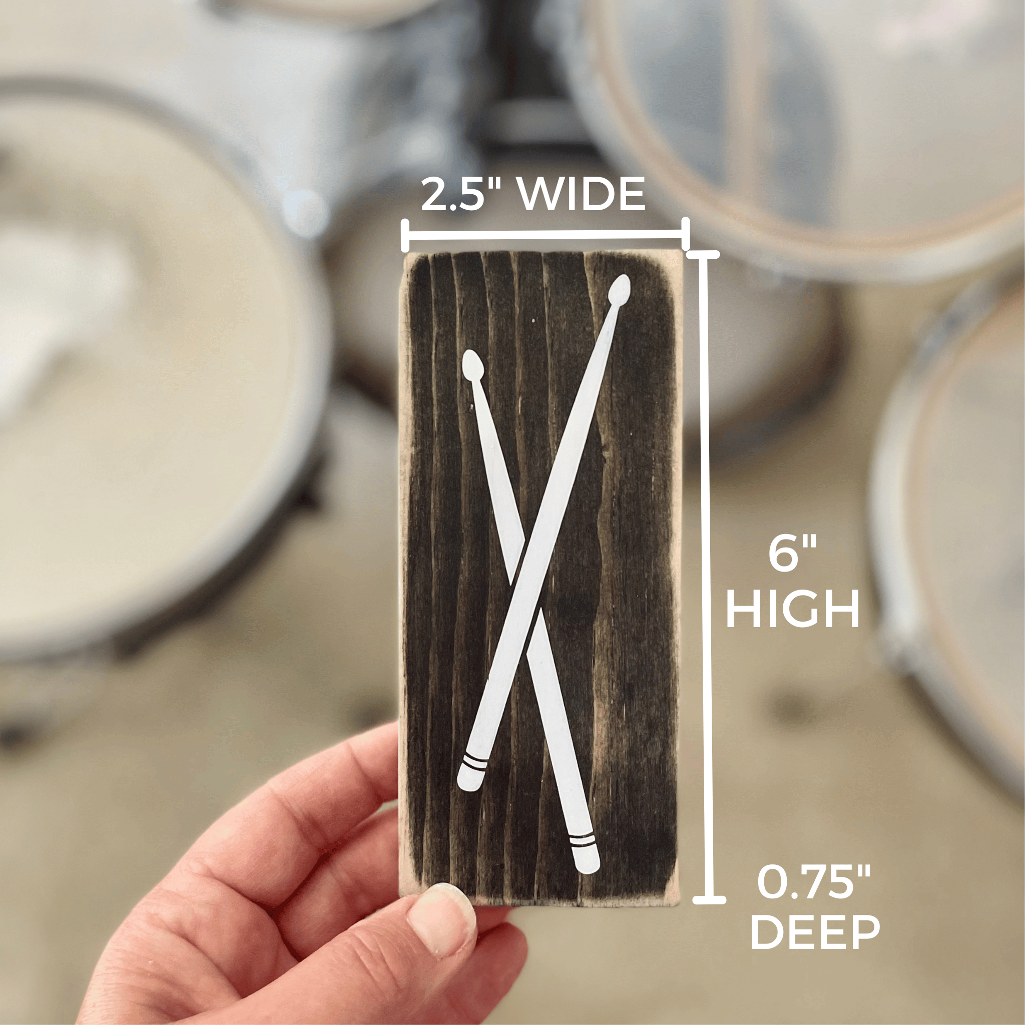 shows the dimensions of the sign with drumsticks on it, which are 2.5" wide, 6" high and 0.75" deep