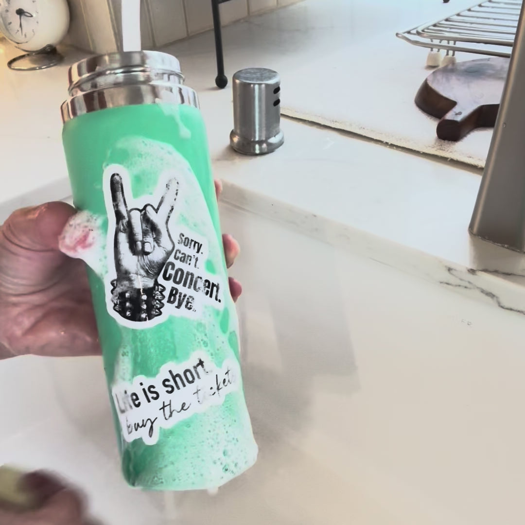 a water bottle with stickers on it is being washed in a sink