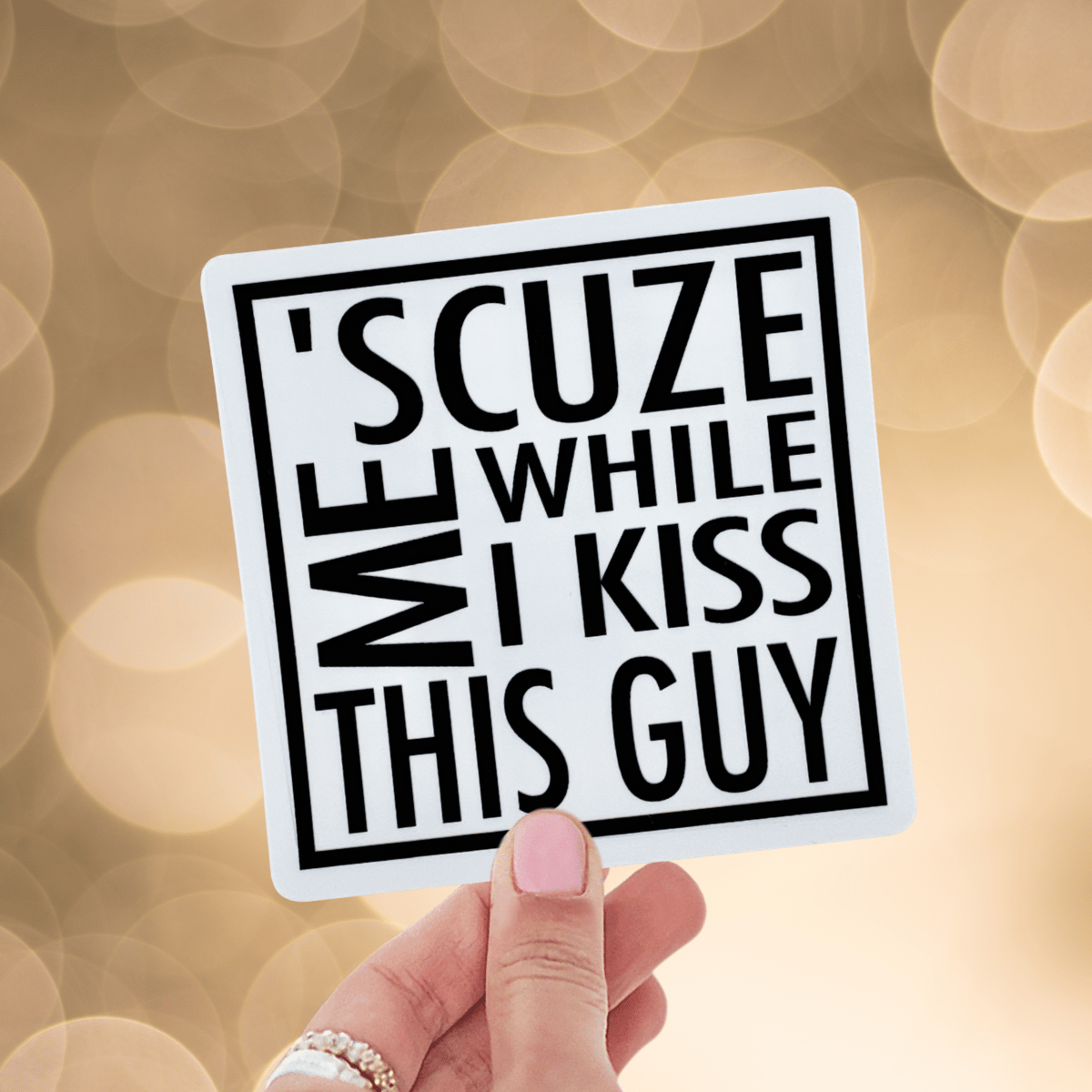 Hand holding a sticker with text against a blurred background