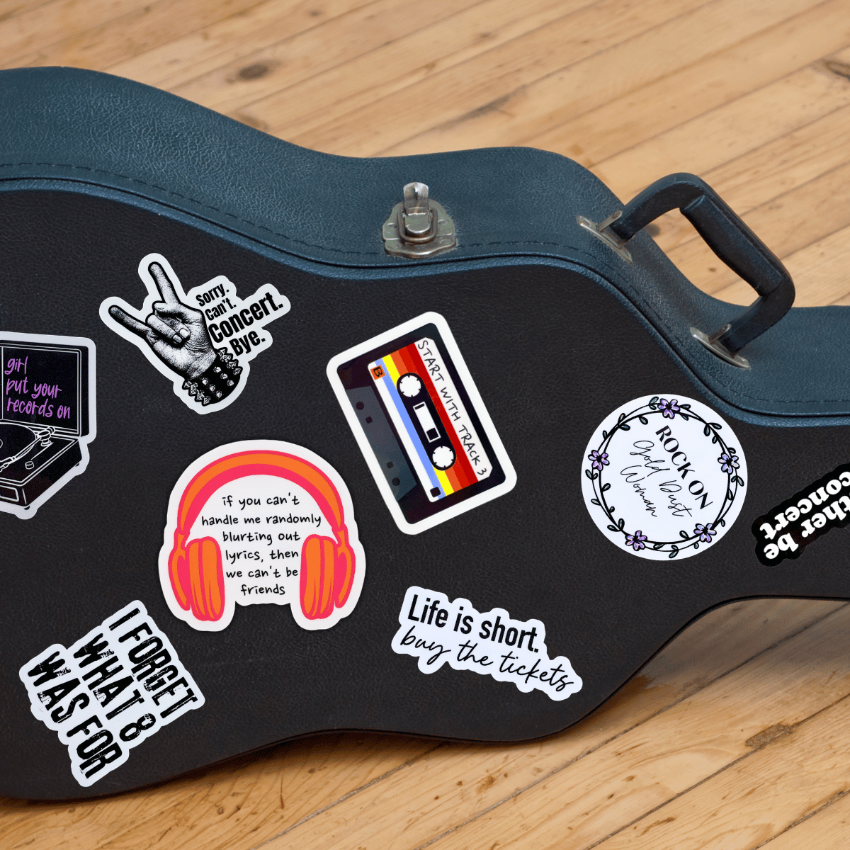 Black guitar case with various stickers on a wooden surface