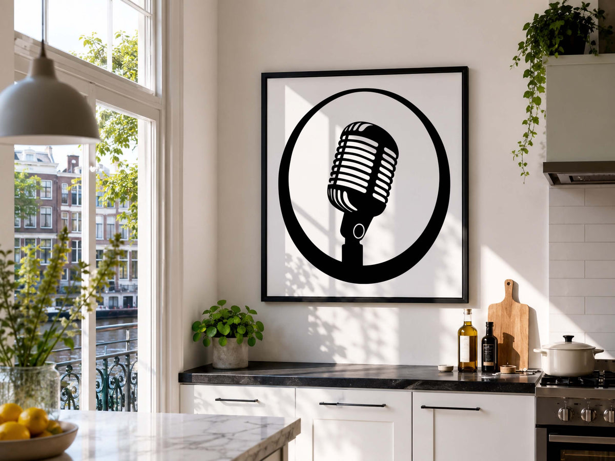 A framed black and white art print of a retro microphone hanging on a white kitchen wall above a counter with plants and kitchen items.