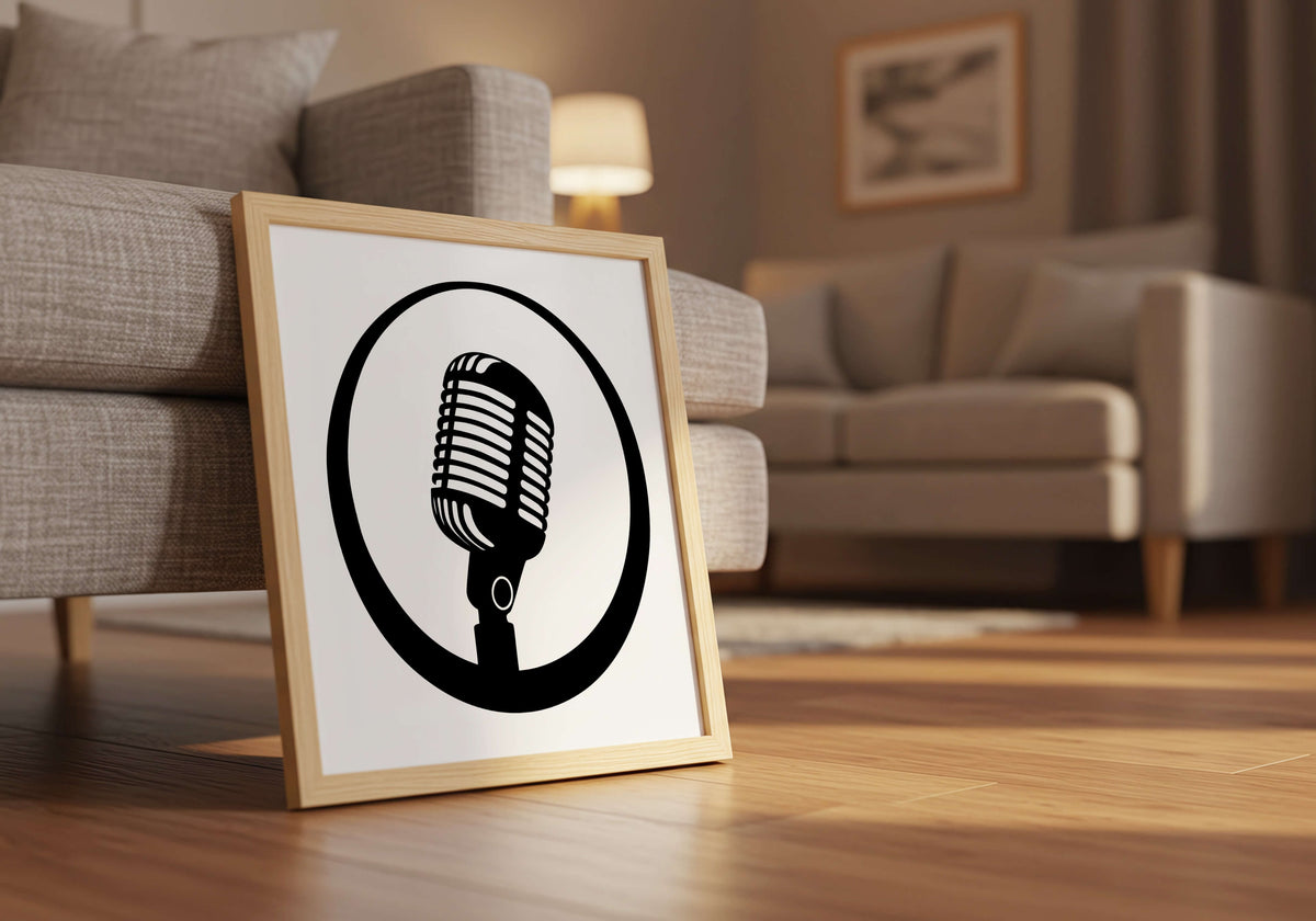 A framed art print featuring a black vintage microphone icon on a white background, leaning against a gray sofa on a wooden floor in a modern living room setting.
