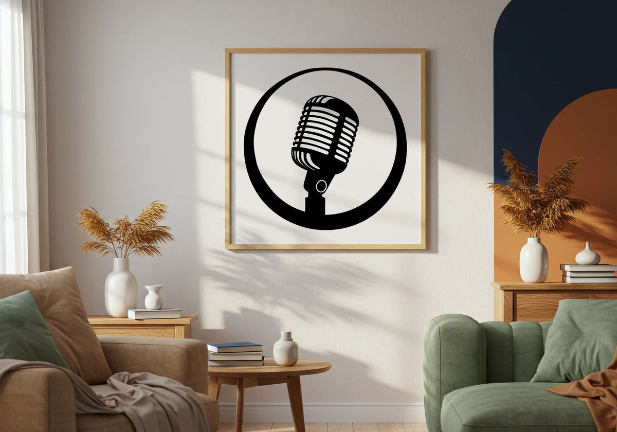 A framed black and white graphic print of a retro microphone inside a circle, hanging on a wall in a modern living room setting with a beige armchair, green sofa, and wooden side tables.